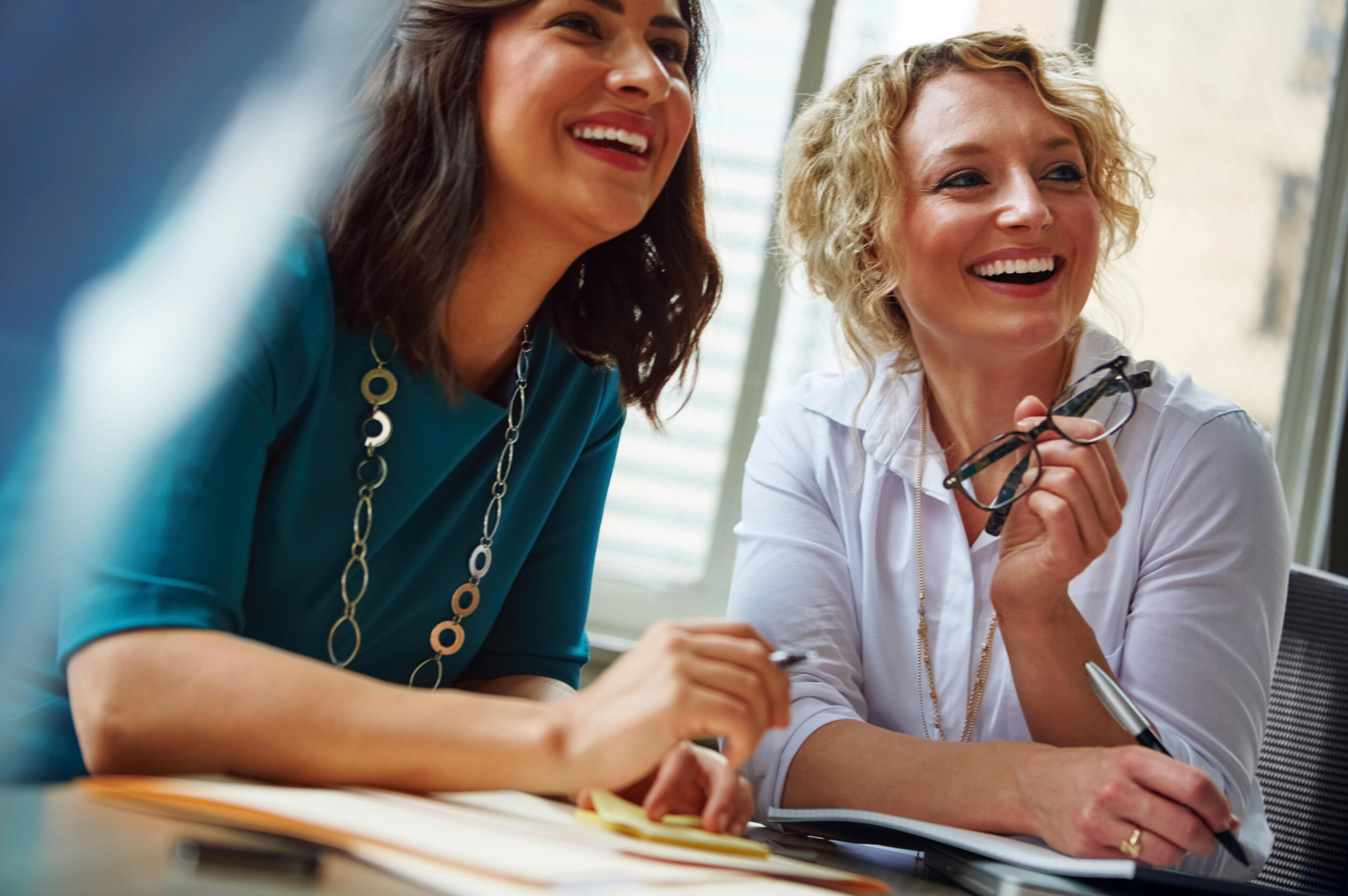 Two women smiling and collaborating at an office